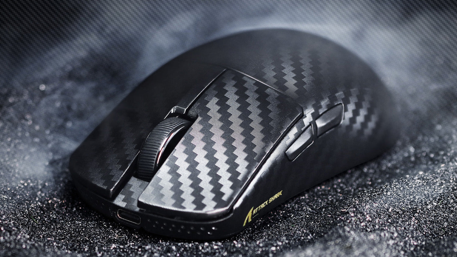 Black gaming mouse with carbon fiber pattern texture, featuring side buttons and a ribbed scroll wheel, displayed on a dark sparkly surface