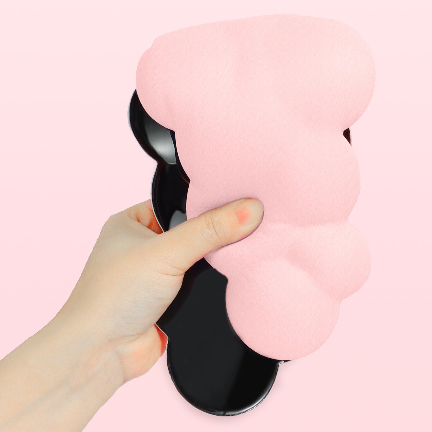 Hand holding a pink cloud-shaped ergonomic wrist rest with anti-slip base.