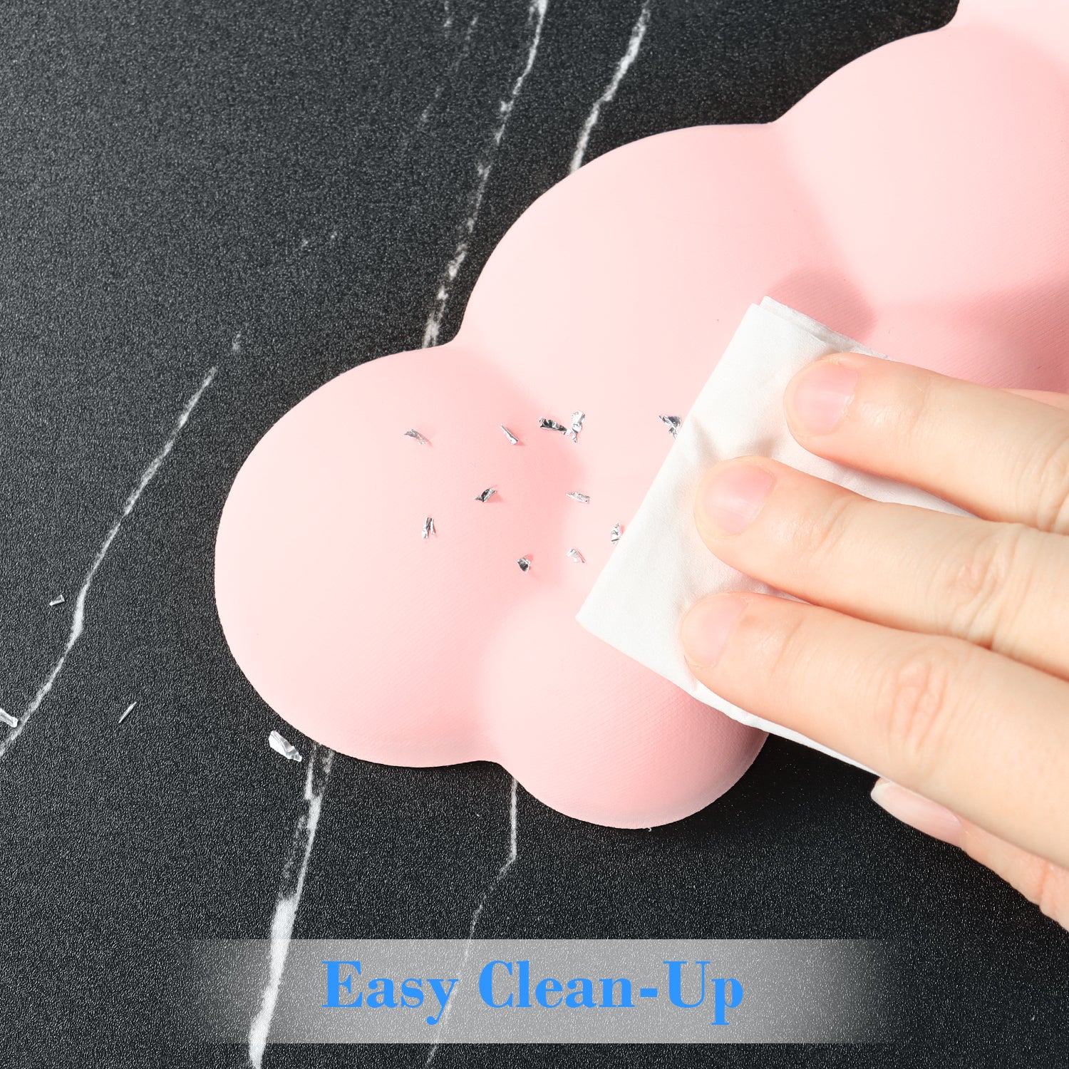 Hand cleaning a pink cloud-shaped wrist rest, easy clean-up surface.